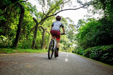 woman cycling on bike path at park on sunny day