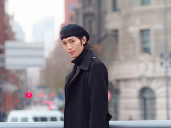 portrait of handsome chinese young man wearing black overcoat, sweater and trousers standing on shanghai street, side view, male fashion, cool asian young man lifestyle.
