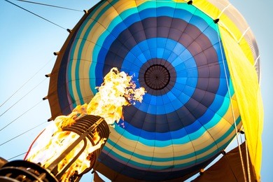 hot air from a gas burner fills the dome of the balloon