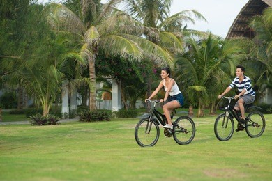 smiling vietnamese couple riding on bikes in the park: health lifestyle concept