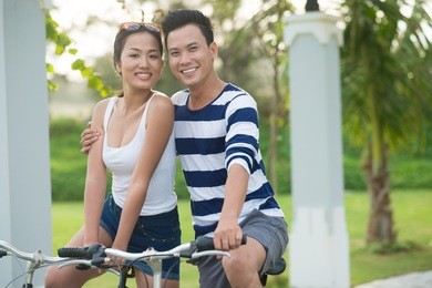portrait of happy young couple riding bicycles in the park