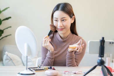 beauty blogger, asian young woman, girl vlogger makeup face, showing, reviews cosmetics products while recording video, tutorial to share on social media. business online influencer on smartphone.
