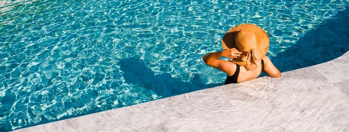 young asian woman with hat relaxing beside the pool at luxury hotel. travel and summer concept background.,cover banner concept vocation summer