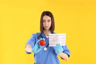 female trainee nurse with heart and ecg on yellow background
