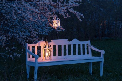 lantern with burning candle on spring cherry tree