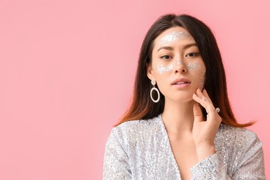 portrait of fashionable asian woman with glitter makeup on color background