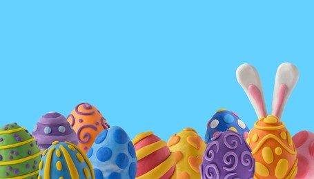 easter greeting card with bunny ears and easter eggs. handmade from plasticine on a blue background with copy space. 3d artwork