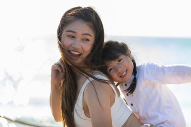 happy asian mom holding her daughter playing together on the beach with fresh air.happy outdoor little girl hugging mother smile and love having fun enjoy with sunset on the beach.mother day concept