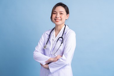 young asian female doctor standing on blue background