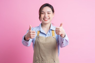 young asian waitress standing on pink background