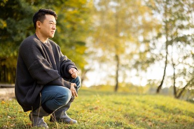 portrait of asian man resting on lake shore. concept of leisure, hobby and weekend in nature. autumn day