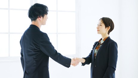 asian male businessman and female businesswoman shaking hands