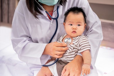 woman doctor using a stethoscope, checking the respiratory system and heartbeat of a 3-months-old baby newborn, to baby newborn and  health care concept.