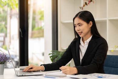 asian businesswoman sitting at a desk young woman working data analysis charts financial documents with laptop in the office