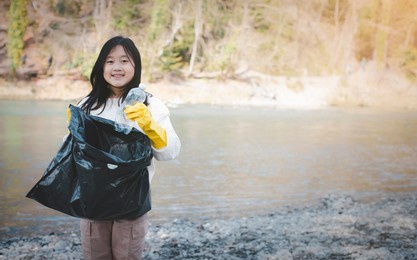 earth day concept, girl teens pick up garbage in litter bags, clean-ups in nature to recycling in their communities, clean river and protect the environment from pollution, conservation nature.