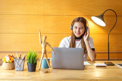 young attractive asian female student wear earphone listen to digital online course.