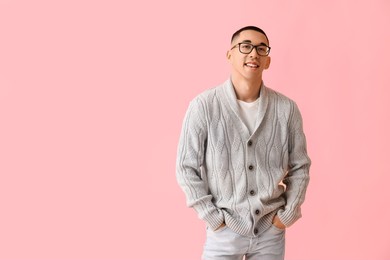 handsome young asian man in knitted sweater on pink background