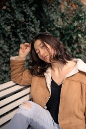young asian woman on bench at city park.