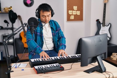 young chinese man singer singing song playing piano keyboard at music studio