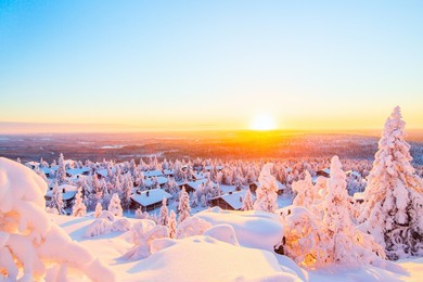 stunning sunset view over wooden huts and snow covered trees in finnish lapland
