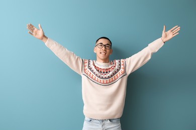 handsome young asian man in knitted sweater on blue background
