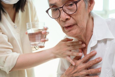 asian senior woman coughing choking while drinking water or eating food,danger or risk of lung infection,disease of silent aspiration pneumonia,old elderly patient choking water after taking the pills