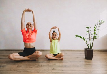 mother and daughter doing meditation and yoga, doing sports and fitness at home