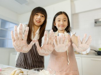a cute and beautiful asian mother and lovely 7 years show hands that dirty and stain with flour during they cooking and making bakery together in modern kitchen.