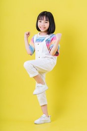 full length image of asian child posing on yellow background