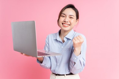 image of young asian business woman holding laptop on pink background