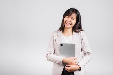 portrait of asian beautiful young woman smiling holding tablet computer, happy lifestyle female teen hugging digital tablet pc, studio shot isolated on white background, university e-book equipment