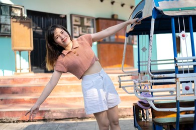 woman traveler by tuk tuk look at bangkok, thailand. woman riding a bus to travel in thailand. the background is an old town.