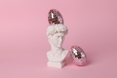 antique bust of david with mirror eggs on a pink background. conceptual pop. minimal easter still life. creative idea