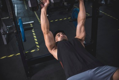 a serious and focused athlete working out chest muscles. doing dumbbell bench presses with a moderate weight.