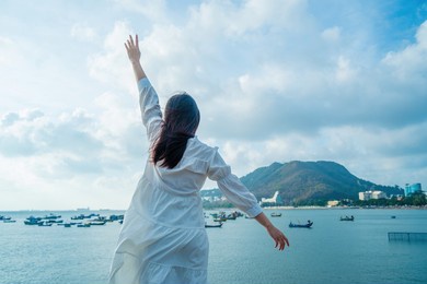 focus back view happy asian girl raises her hands up in front of beach at vung tau. travel concept. concept welcoming, relaxing and enjoying.