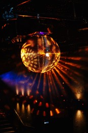 disco ball hanging on the ceiling of the disco rays of light are reflected from it.