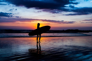 surfer girl silhouette. surf woman walking with surfboard on the beach. golden hour beautiful colors