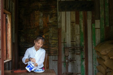 asian women wearing traditional costumes pouring tea in the rice mill