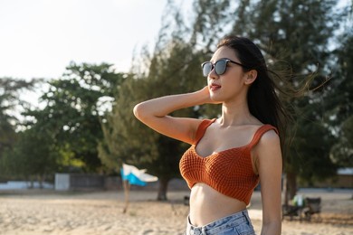 portrait of asian young woman standing on beach during summer time. attractive female traveler feel happy and relax taking a deep breath while travel for holiday vacation trip in tropical sea island.