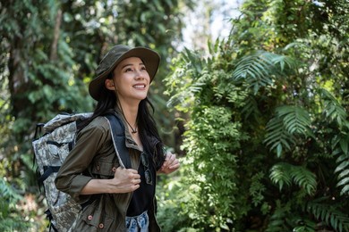 asian young beautiful female backpacker traveling alone in forest wild. attractive girl traveler look around and explore while walk in nature wood with happiness and fun during holiday vacation trip.
