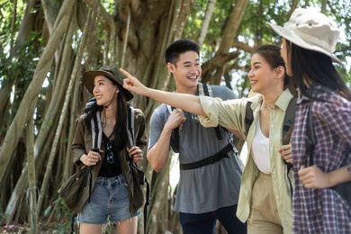 group of asian backpacker people have fun travel in forest together. attractive man and woman friends traveler walking and exploring nature wood with happiness during holiday vacation trip on summer.