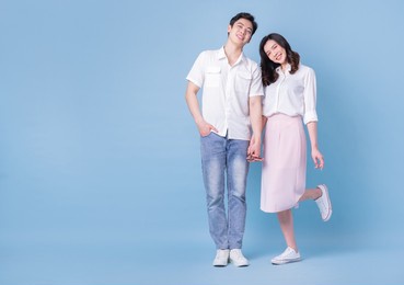 full length image of young asian couple on blue background