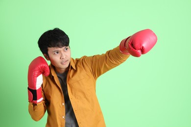 the young adult asian man with smart casual clothes standing on the light green background.