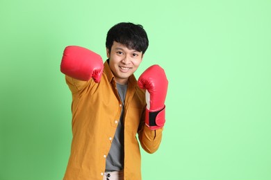 the young adult asian man with smart casual clothes standing on the light green background.