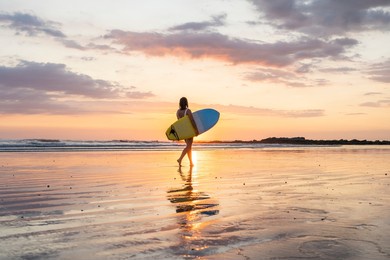 surfer girl silhouette. surf woman walking with surfboard on the beach. golden hour beautiful colors