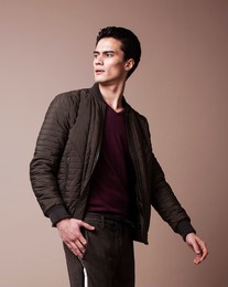 young pretty asian man posing in fashion style on light brown background, lifestyle people concept
