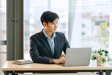 serious casual asian business man online working on laptop computer screen.