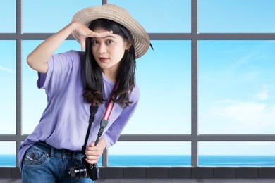 asian woman with a hat and camera looking at something inside the building with blue sky background