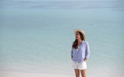 portrait image of a beautiful young asian woman while strolling on the beach by the sea
