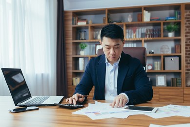accountant-auditor works in a classic office, calculates financial reports, asian businessman works with computer and documents, paperwork
